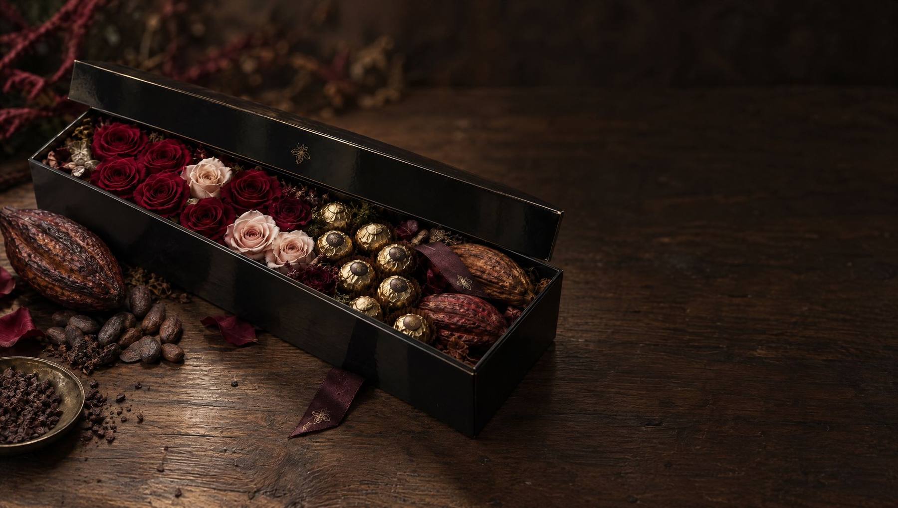 A black lacquered long box of preserved roses and cacao truffles in warm light